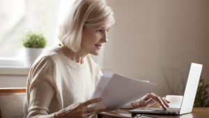 Woman using computer and reading paperwork