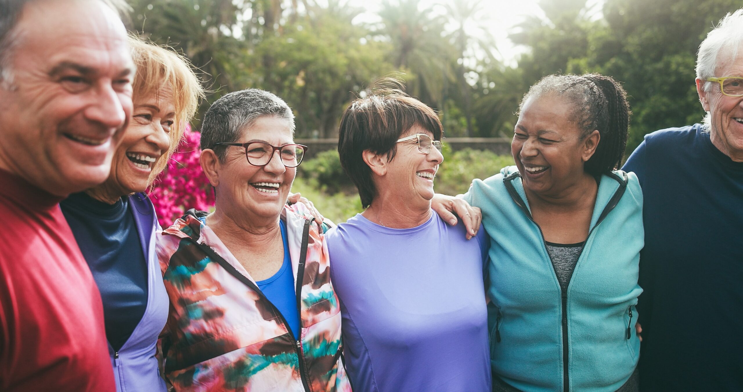 Older people having fun hugging each other after sport workout at city park - Healthy lifestyle helps manage stress.