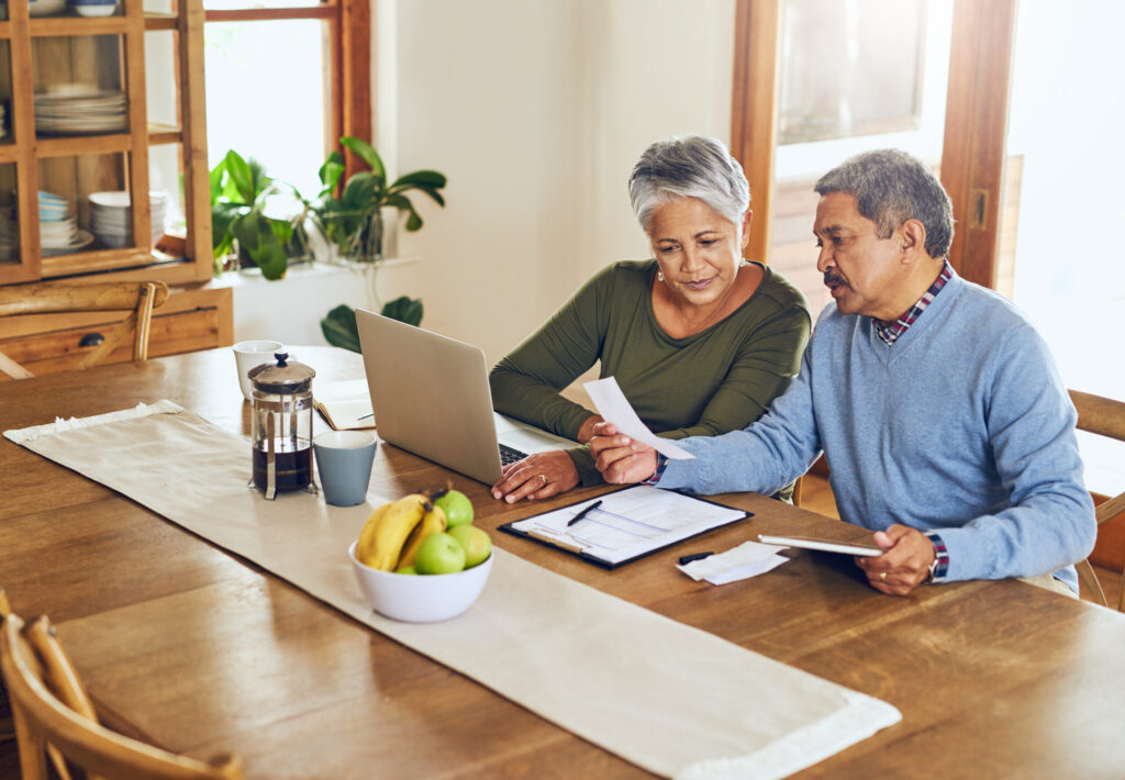 Finance, laptop and older couple with bills, paperwork and receipt documents for life insurance finding ways to save money.