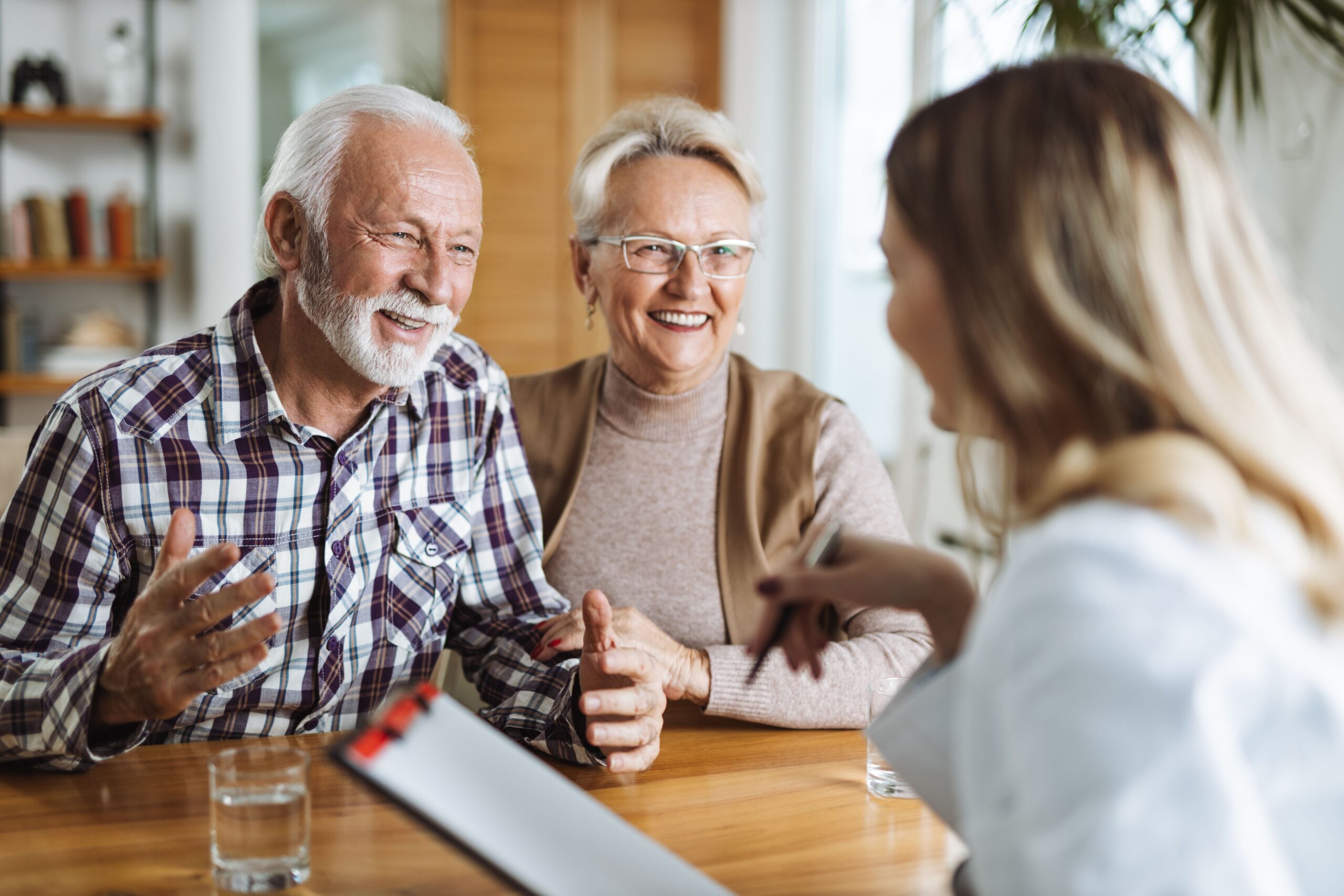 Senior couple discussing healthcare options with a service provider, Medicare provides a low income subsidy for costs with Part D Extra Help redetermination
