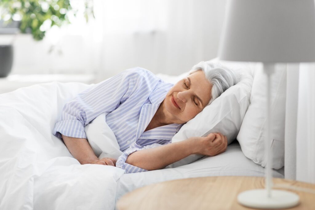 Older woman sleeping in bed, going to bed early to get better sleep.