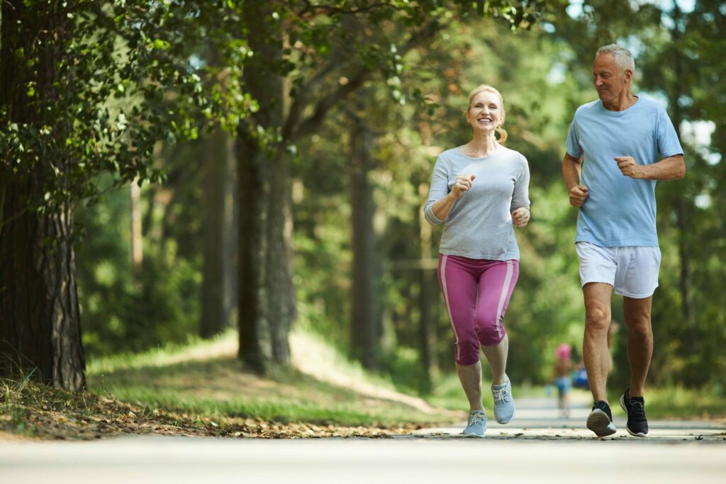 Active and healthy aged couple running in natural environment on summer morning. Physical activity is a good way of managing prediabetes.