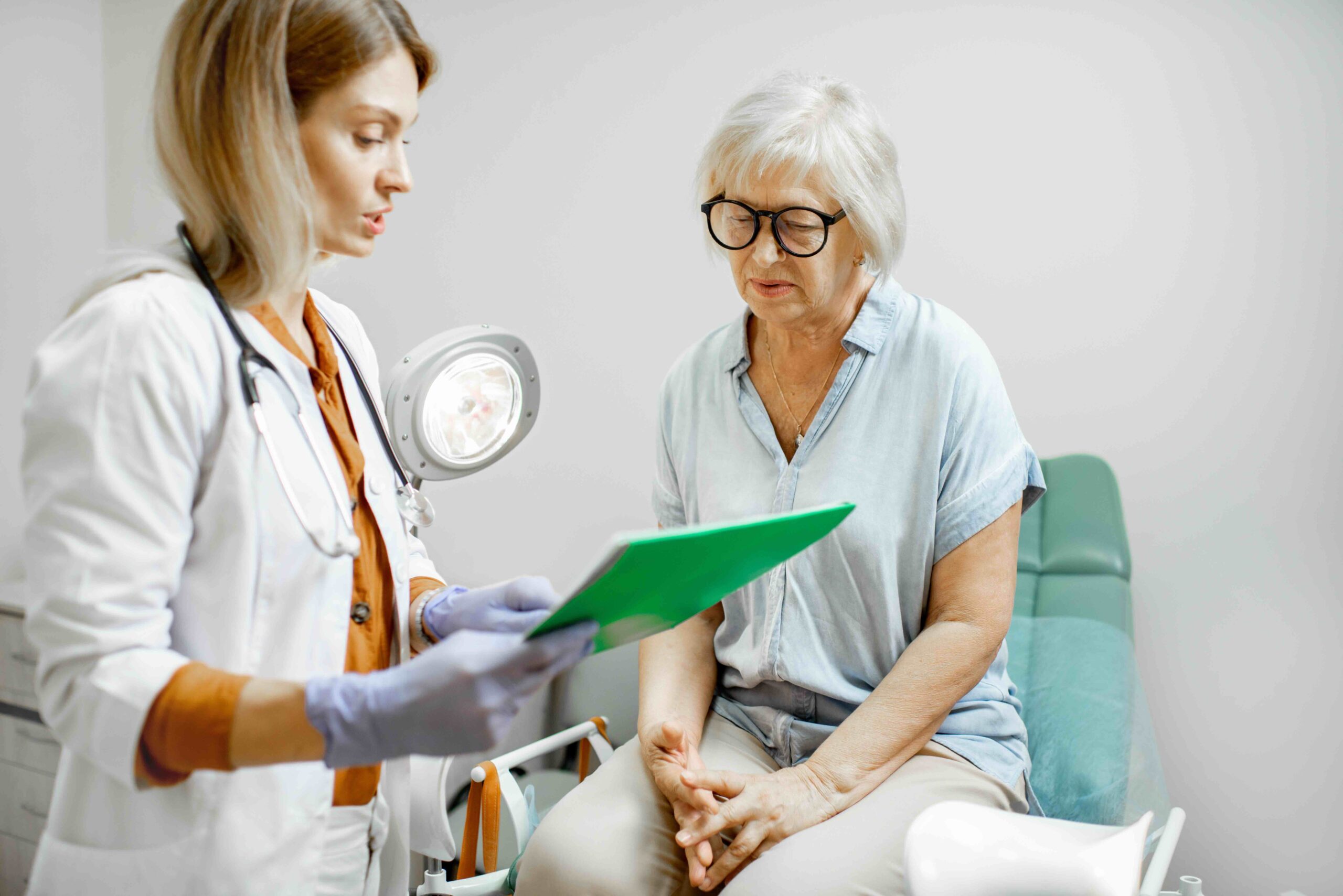 Senior woman sitting in a chair during a medical consultation with a physician. Speak with your care team about managing costs with Medicare coverage for ESRD.