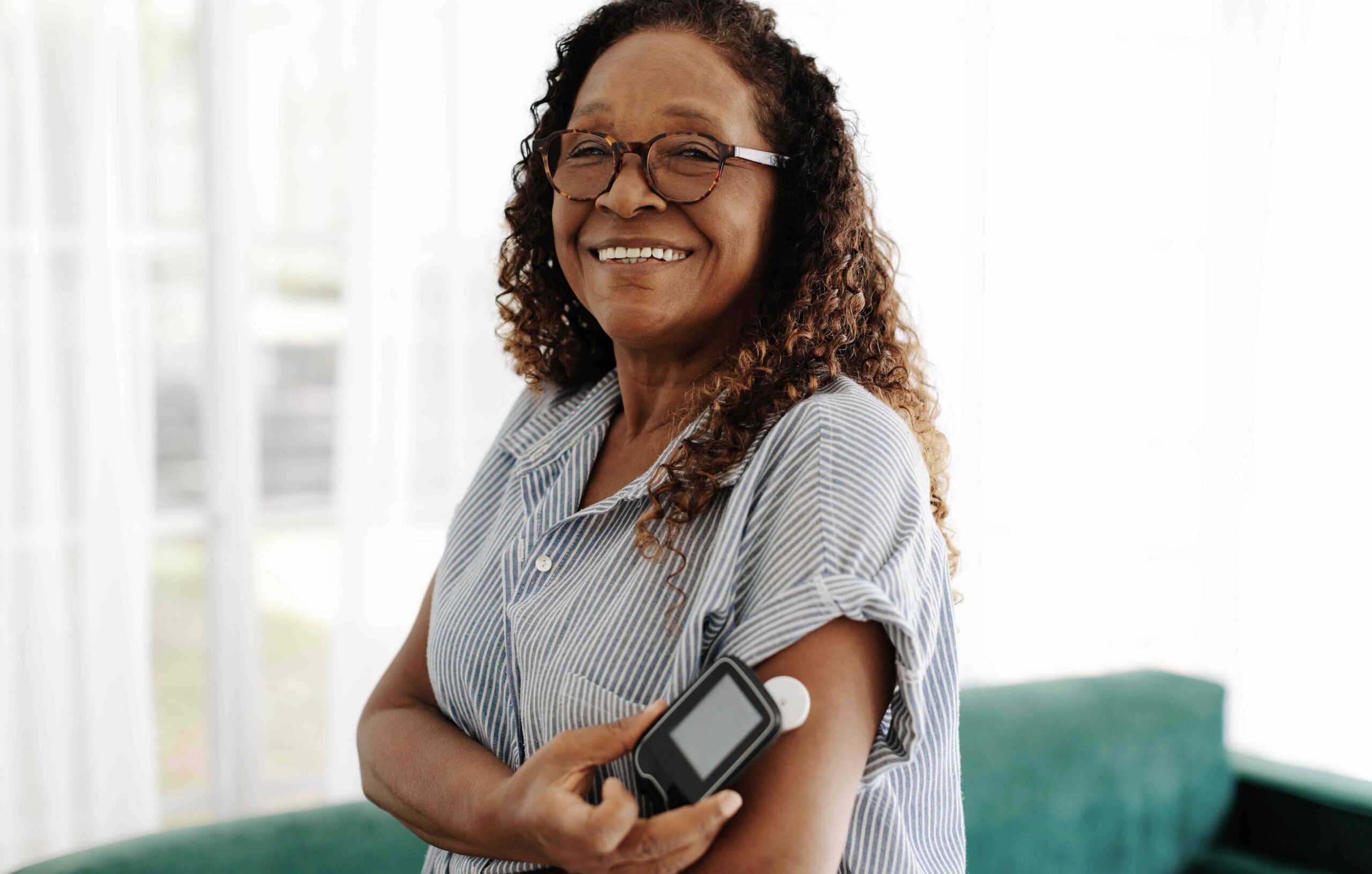 An older black woman holding her mobile phone to a continuous glucose monitor on her left arm. Products like these can be covered by Medicare Part B or Medicare Advantage plans. Learn more about Medicare coverage for diabetes in this article.