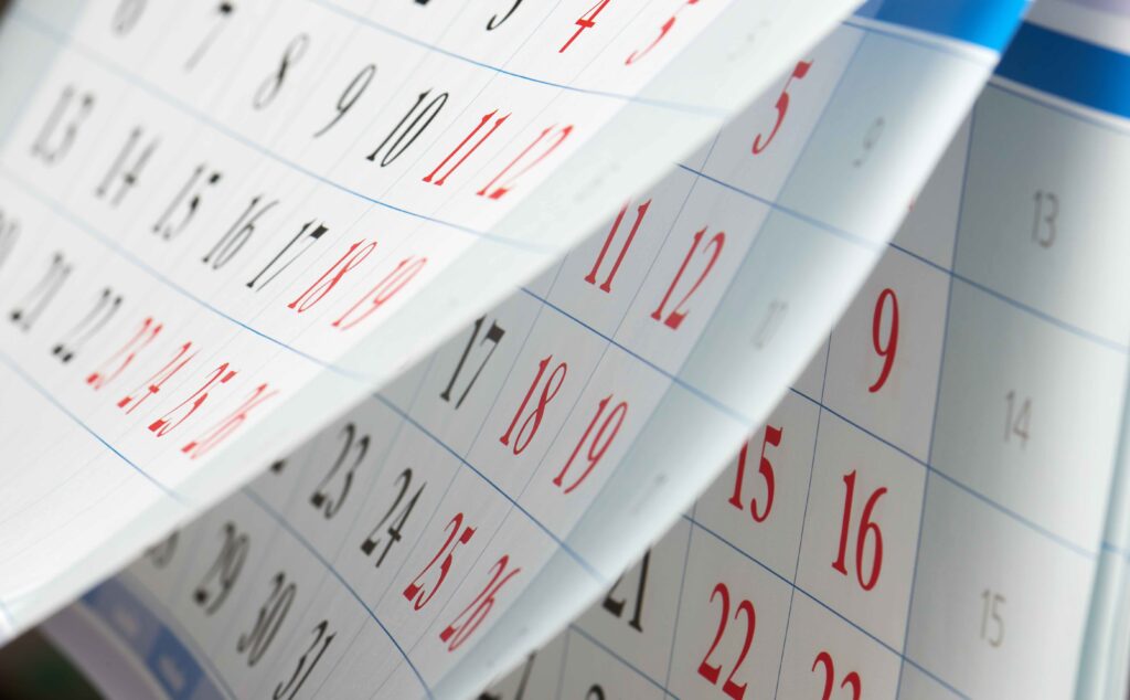 Flipping of sheets of calendar with black and red numbers. Not knowing relevant timelines for enrollment periods is one of the common Medicare enrollment mistakes.