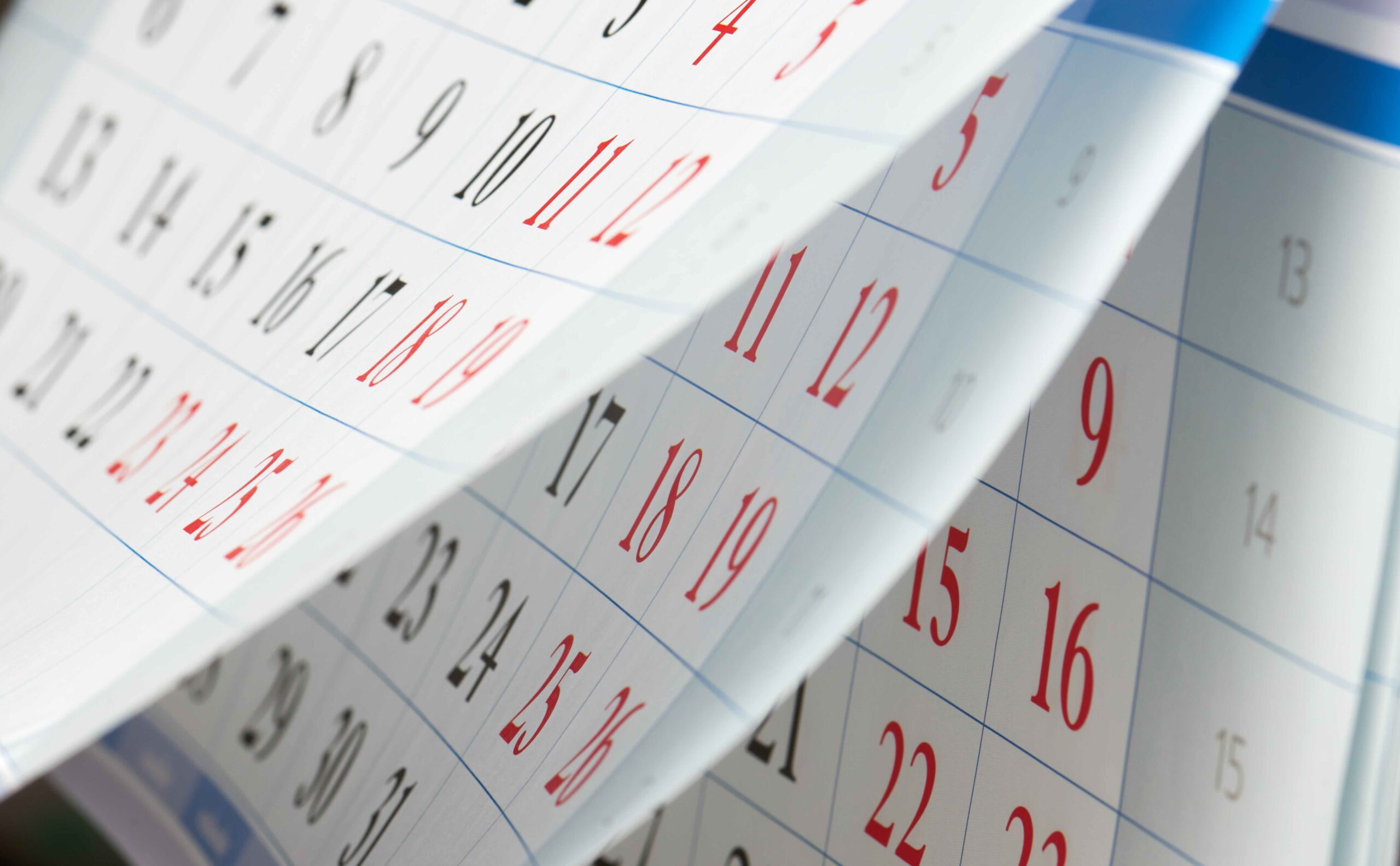 Flipping of sheets of calendar with black and red numbers. Not knowing relevant timelines for enrollment periods is one of the common Medicare enrollment mistakes.