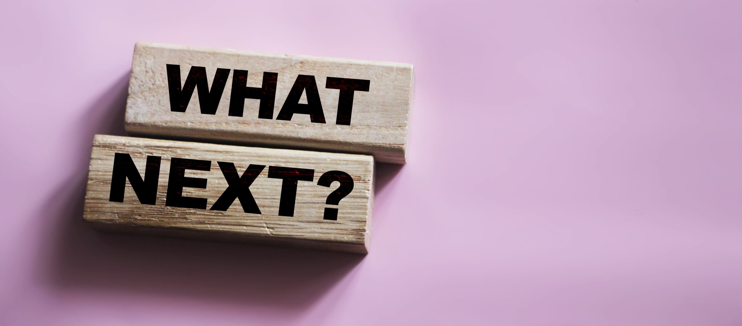 The words What Next on wooden blocks, close up shot, view from above. Next steps concept for Medicare news.