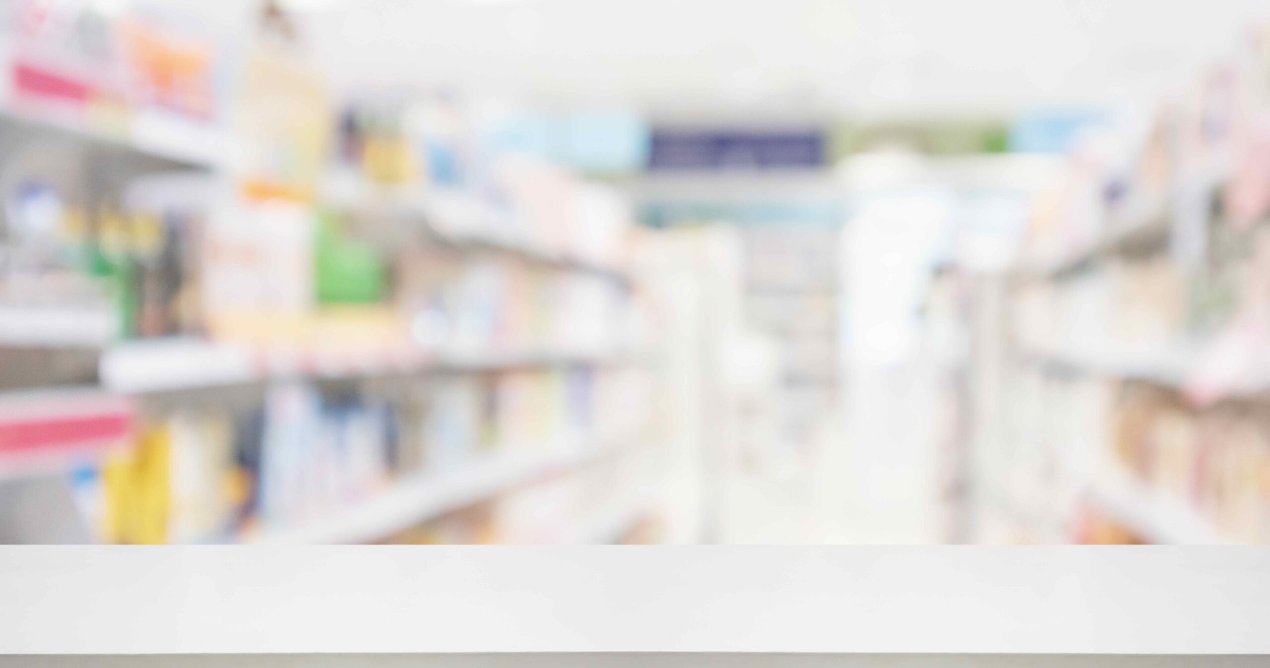 Pharmacy drugstore counter with medicine and vitamin supplement on shelves. Image is blurred as a concept for OTC benefits through Medicare Advantage plans.