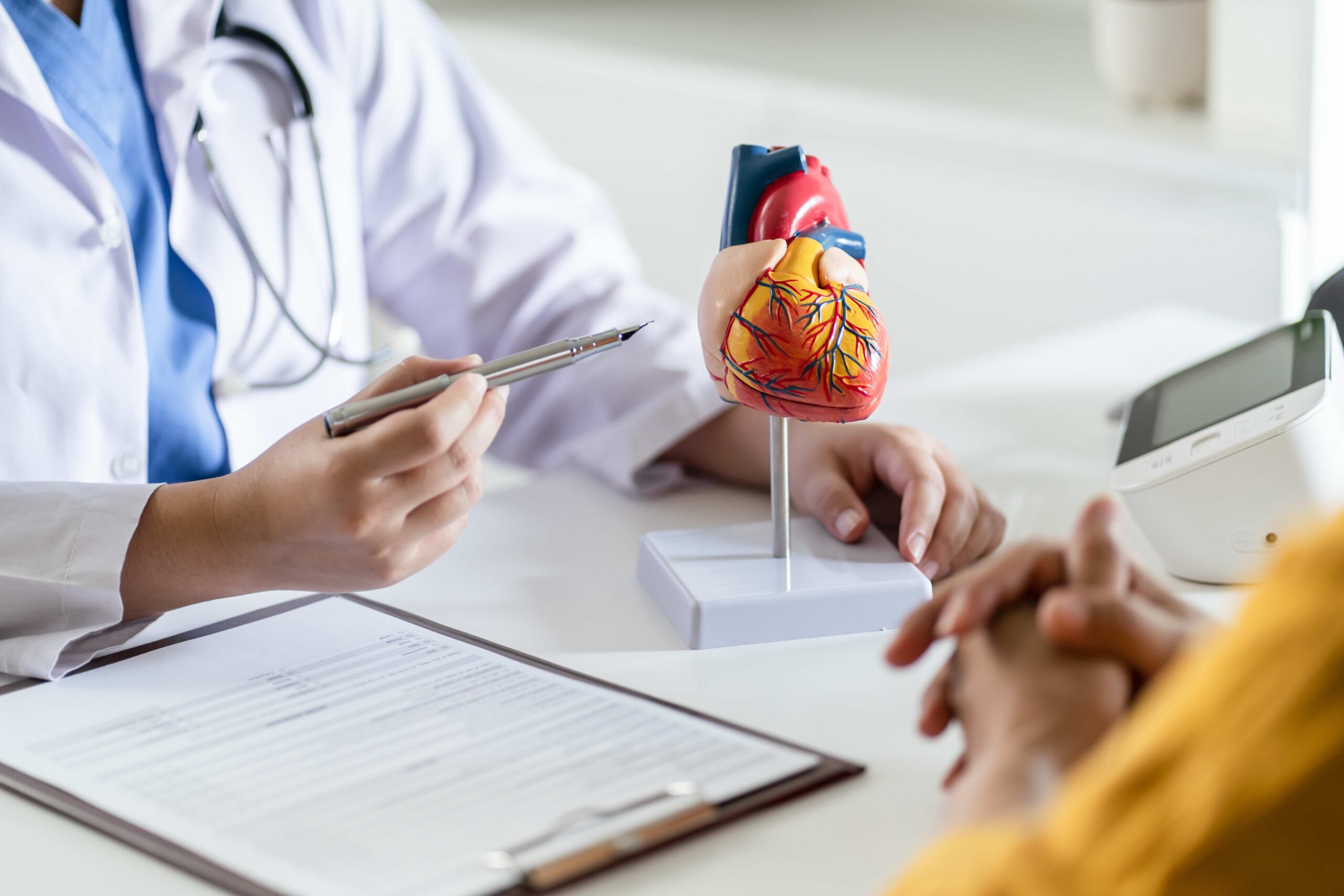 Doctor cardiologist while consultation showing anatomical model of human heart with aged patient talking about heart diseases. Concept for article Medicare Advantage and heart disease.