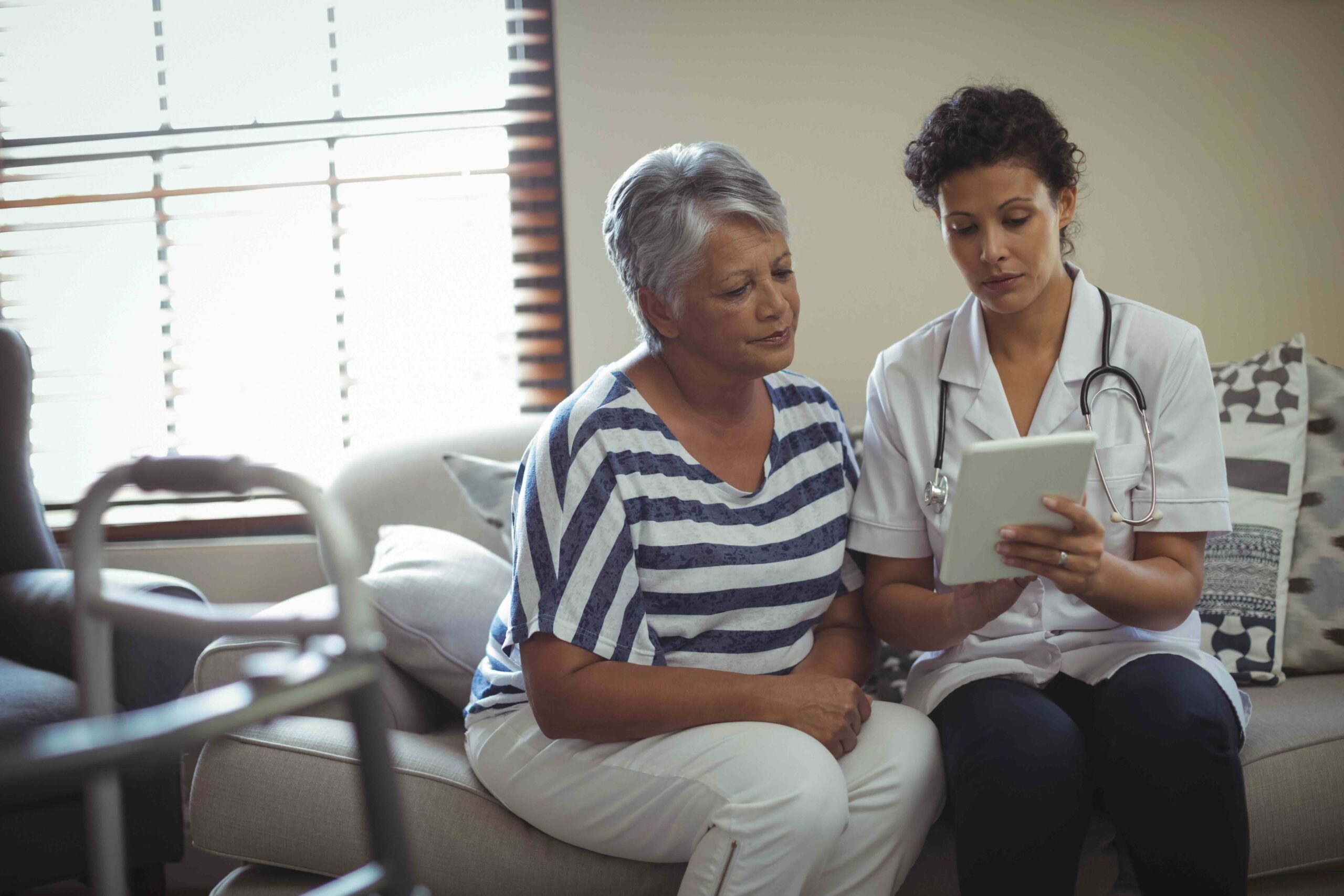Female doctor discussing treatment over digital tablet with senior woman. Treatments and products may be subject to prior authorization under Medicare Advantage plans.