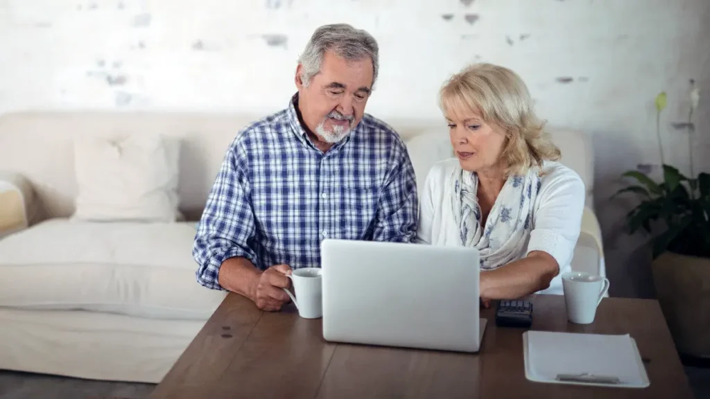 A couple sit on the sofa looking at a laptop. Concept for evaluating Medicare Advantage
