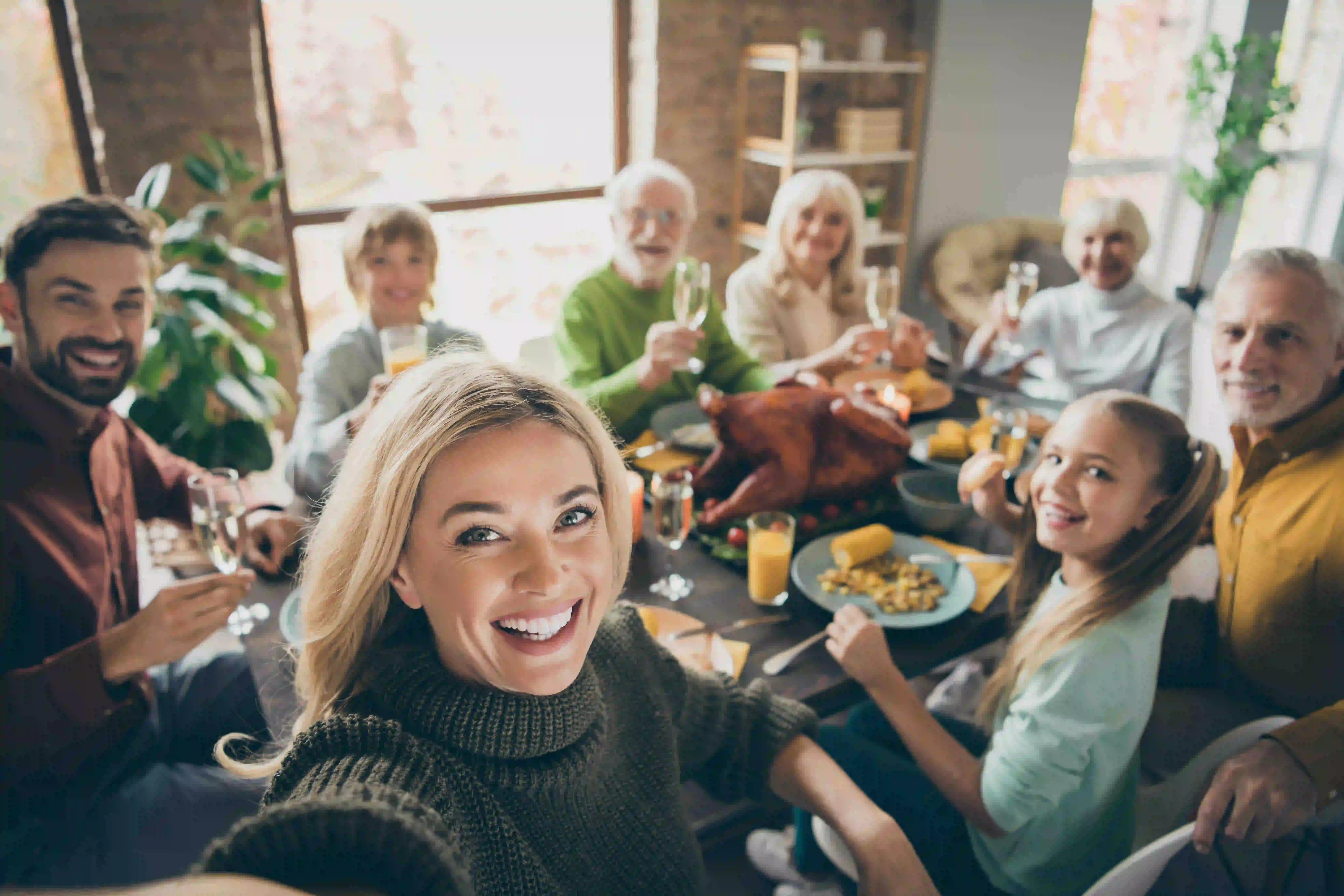 A woman takes a selfie of her multi-generational family sits for Thanksgiving dinner. The spread includes diabetic Thanksgiving dinner swaps.