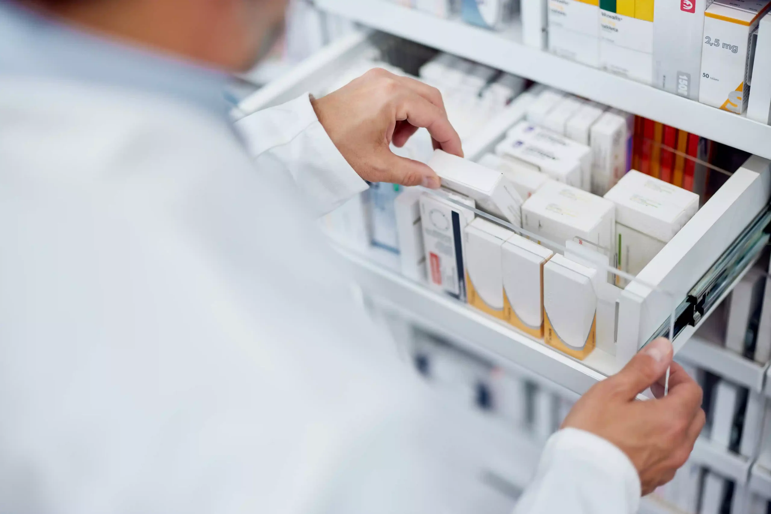 A pharmacist opening a drawer of medications in a pharmacy. Concept for Medicare Part D prescription coverage.