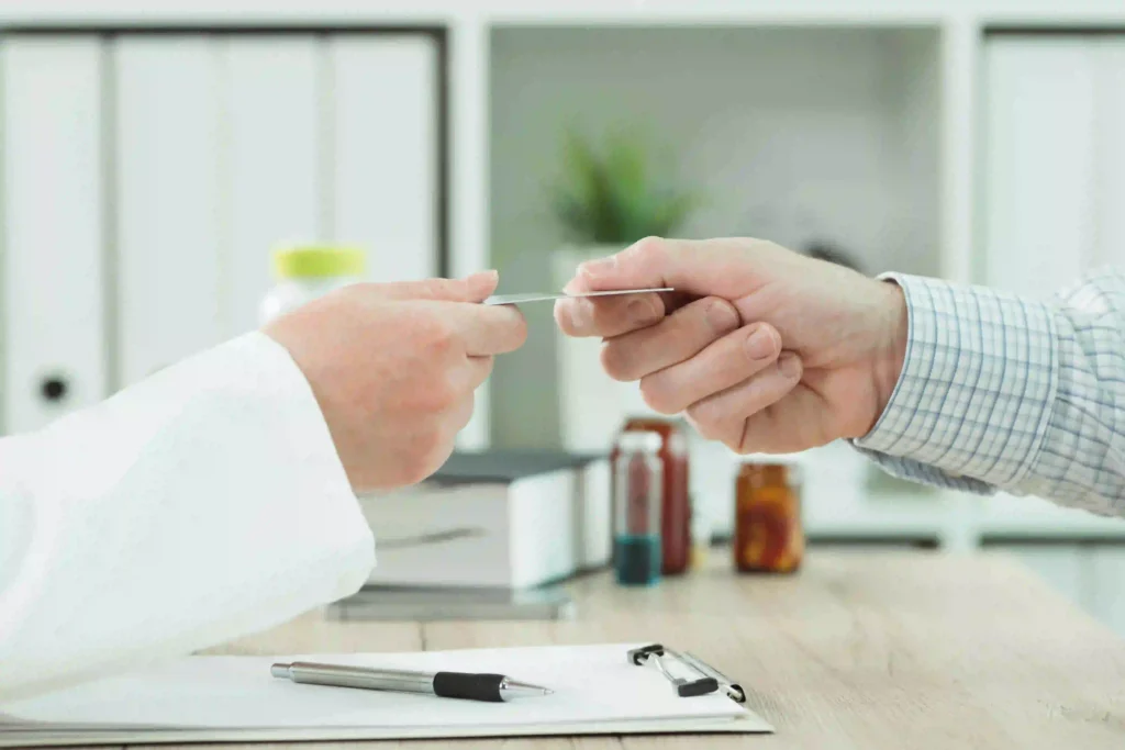 A patient handing a physician their Medicare card at a doctor’s office