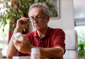 older man consulting current prescription medication while evaluating new medicare part d changes